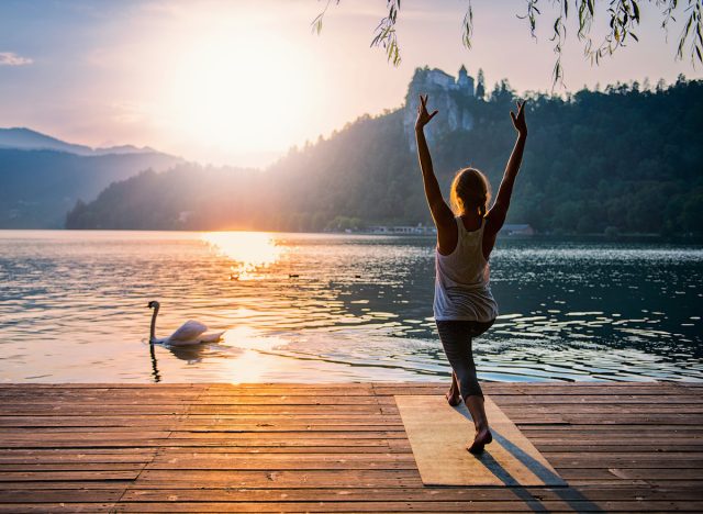 woman on lake dock demonstrating yoga exercise incredibly fit people do