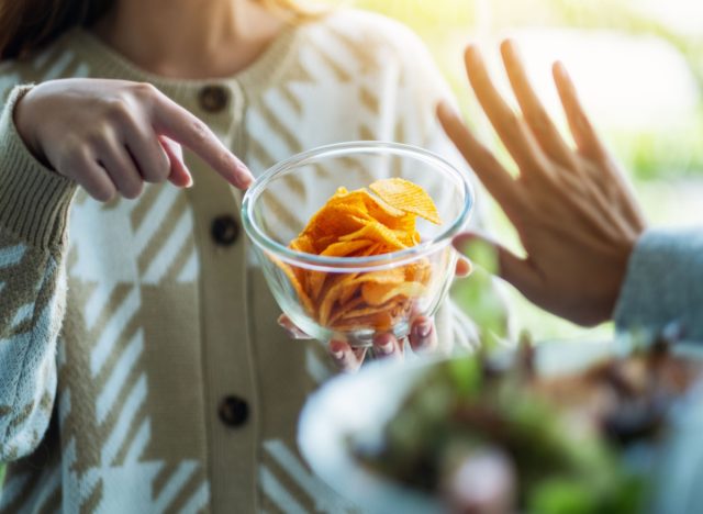 woman refusing potato chips and choosing vegetables instead