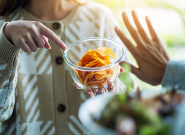 woman refusing potato chips and choosing vegetables instead