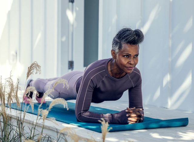 fit mature woman demonstrating the strength training habits that slow aging, doing plank in backyard
