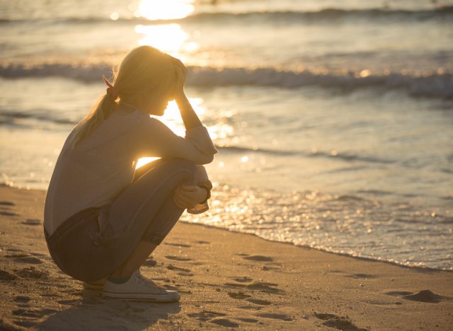 woman upset on beach, demonstrating how to deal with losing a parent