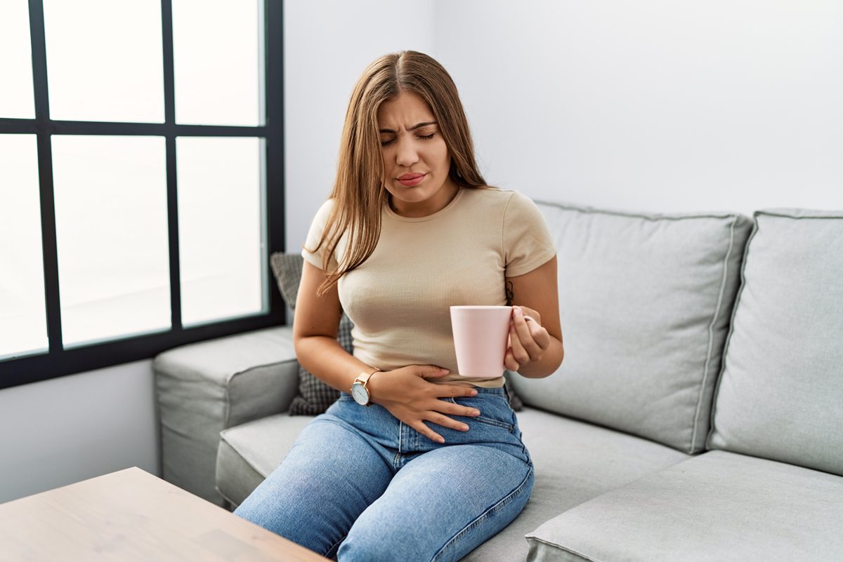 woman with upset stomach drinking tea