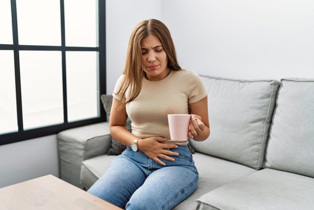 woman with stomach ache while drinking tea