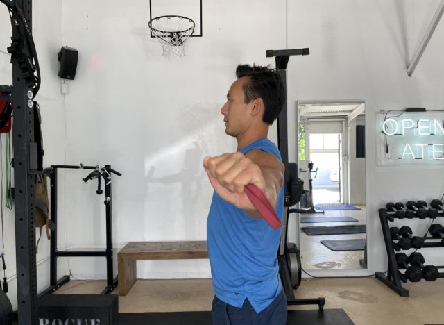trainer performing band pull-aparts, exercise to burn twice the calories