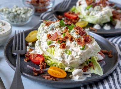 classic wedge salad with iceberg lettuce, blue cheese dressing, bacon, tomatoes, and onions