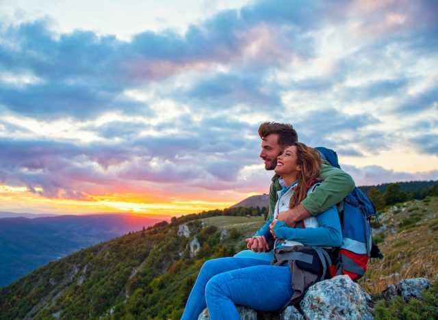 couple inn-to-inn hiking, mountain top at sunset