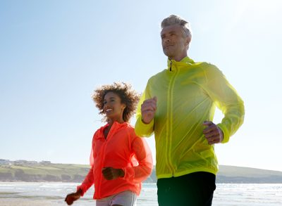 couple jogging on beach, demonstrating getting a fitter body after 40
