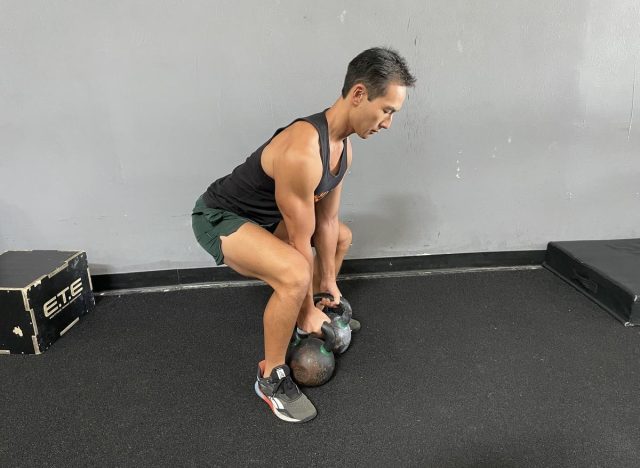 trainer performing double kettlebell deadlift