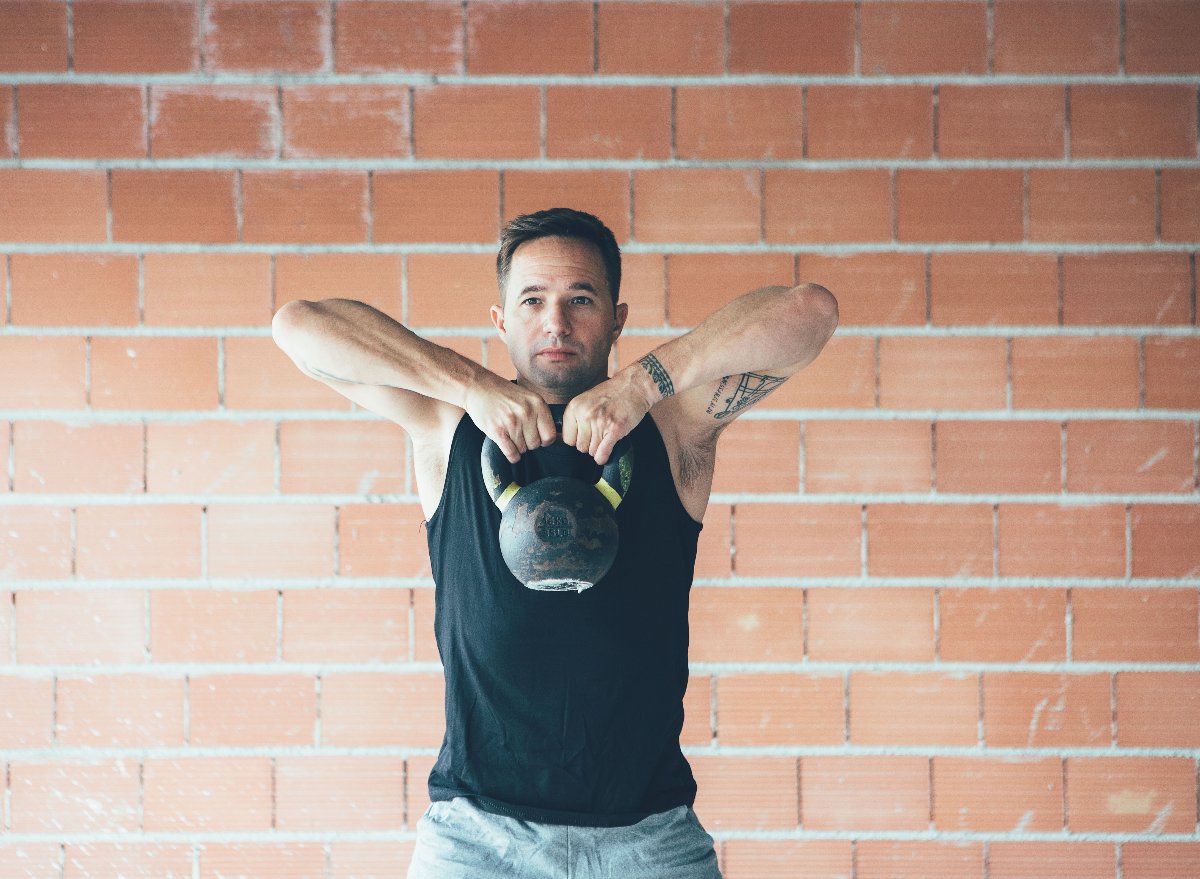 fitness man demonstrating kettlebell exercises to shrink your belly overhang for good