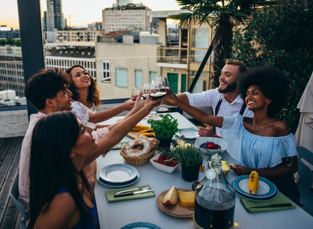 happy friends having rooftop dinner party, tiny things to massively boost your health
