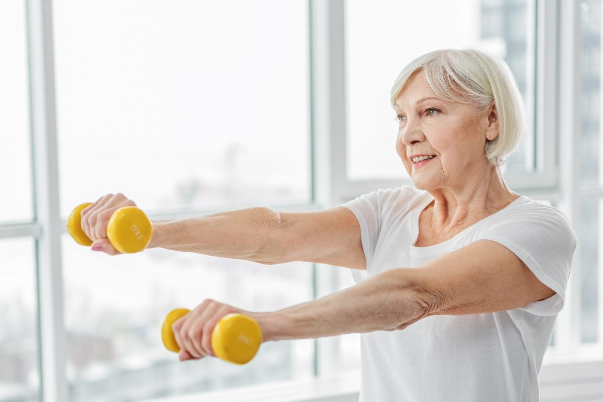 happy mature woman performing dumbbell exercises to live to 100 and beyond