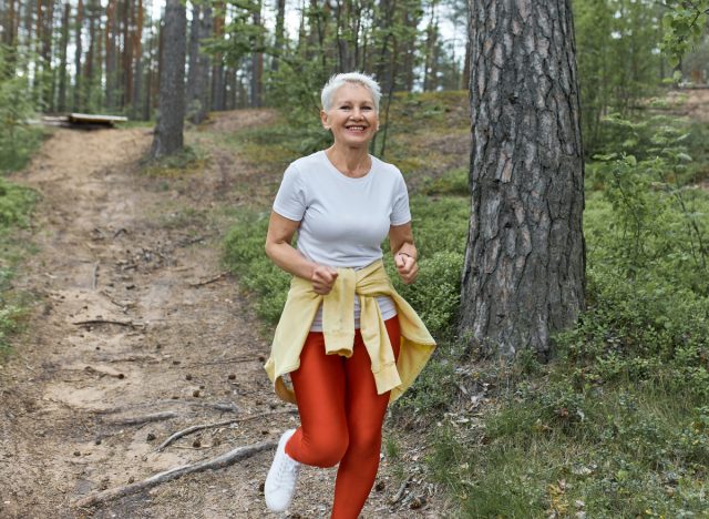happy mature woman in woods demonstrating the plogging habits that slow aging