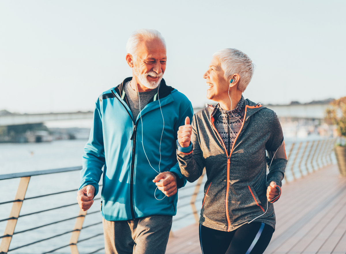 happy senior couple demonstrating the walking habits that slow aging on bridge, fall day