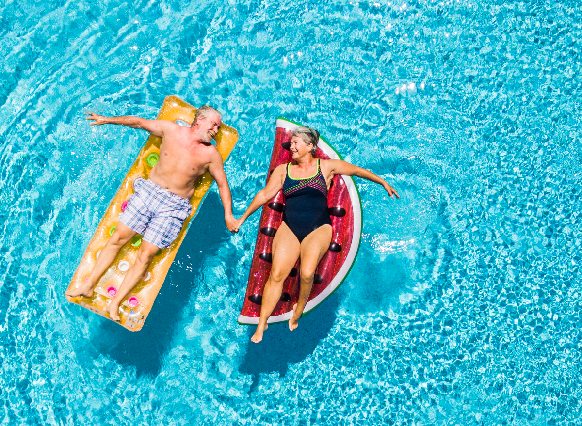 happy senior couple using pool floats, demonstrating sneaky habits to slow down aging