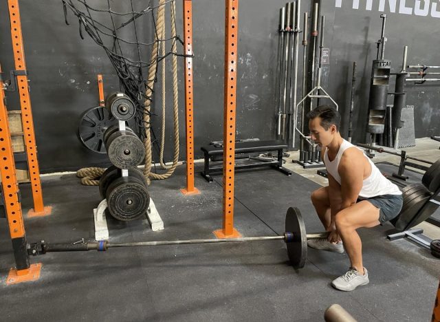 trainer demonstrating landmine deadlift to melt your midriff bulge