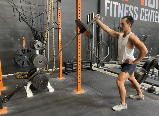 trainer demonstrating landmine shoulder press exercise, concept of strength workouts for flabby arms