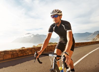fit man biking scenic roads demonstrating cardio exercises to lose visceral fat and slow aging
