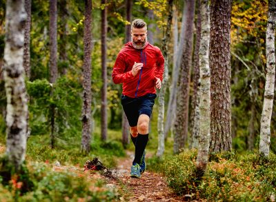 man sprinting through the woods in autumn, fitness habits that slow aging