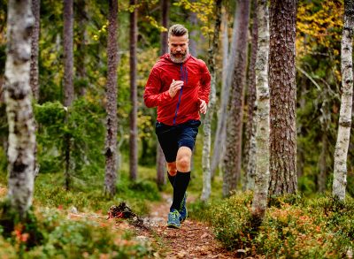 man sprinting through the woods in autumn, fitness habits that slow aging