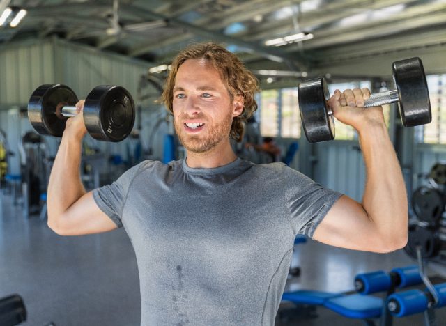 man standing shoulder press, demonstrating workout to get rid of hanging belly fat