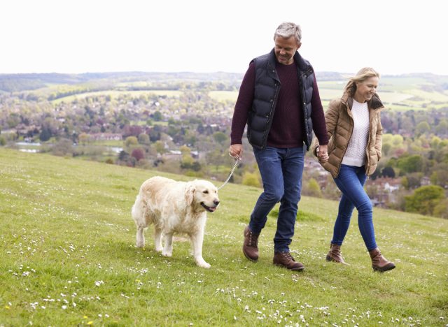 mature couple walking dog, fitness habits that'll help you live to 100