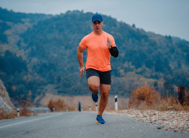 mature man running outdoors in orange t-shirt, demonstrating running habits that are rapidly aging your body