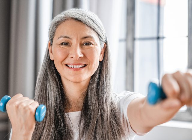mature happy woman with dumbbells demonstrating exercising twice a day