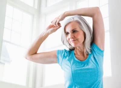 mature woman stretching arms as part of bat wings workout