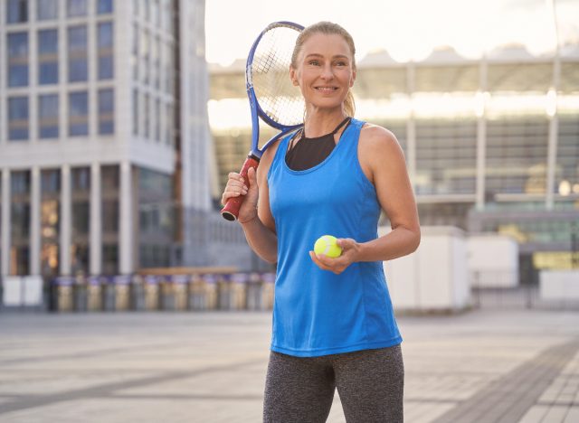 mature woman getting ready to play tennis, one of the leisure activities that extend your life
