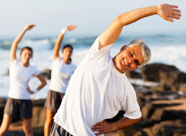 middle-aged man stretching at beach, demonstrating exercise habits for arthritis