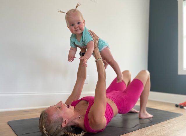 new mom and fitness trainer lovingly holding her baby on a workout mat