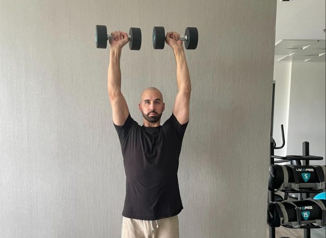 The trainer shows the upper press as part of the exercise for stronger muscles in their 50s