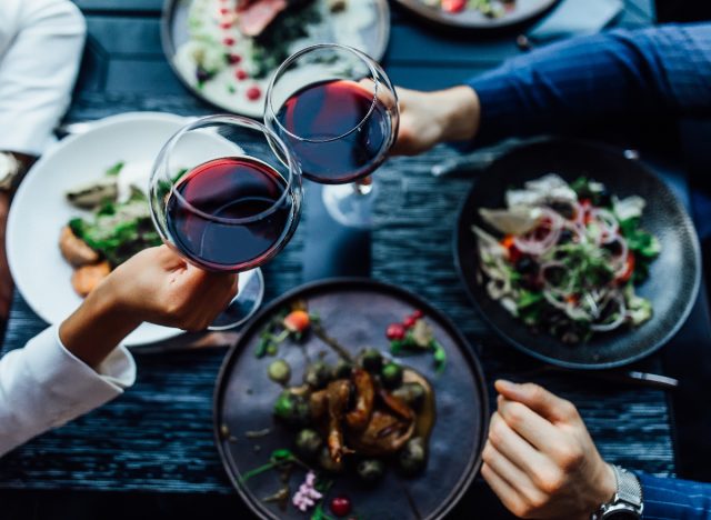 people clinking red wine glasses during dinner