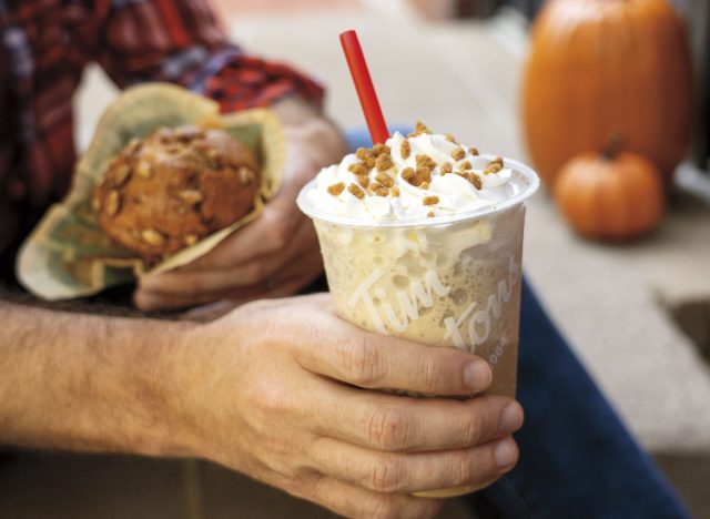 person holding tim hortons' pumpkin spiced iced capp and pumpkin spiced muffin