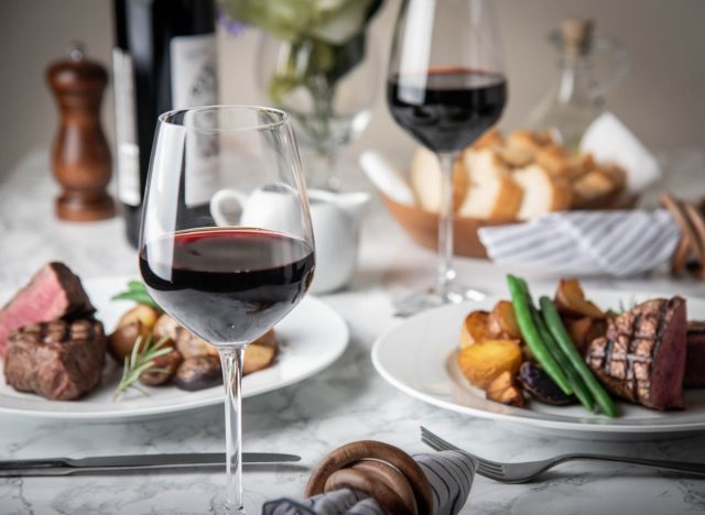 red wine glasses, steak, and veggies