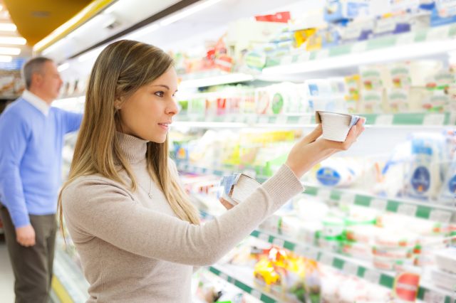 Woman grocery shopping for yogurt in the dairy aisle