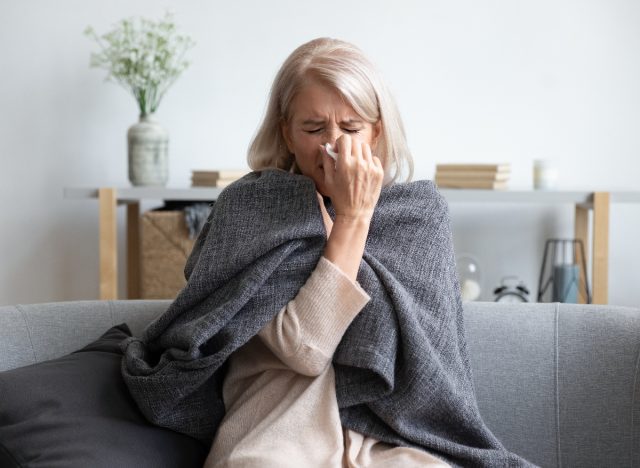 sick woman blowing nose into tissue