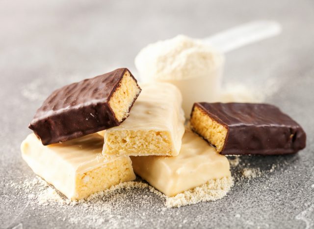 whey protein powder in measuring scoop next to protein bars