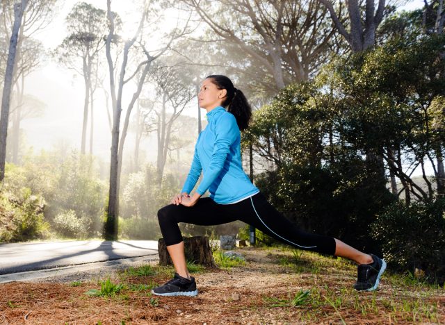 woman performing walking lunges on trail, stretches for weight loss