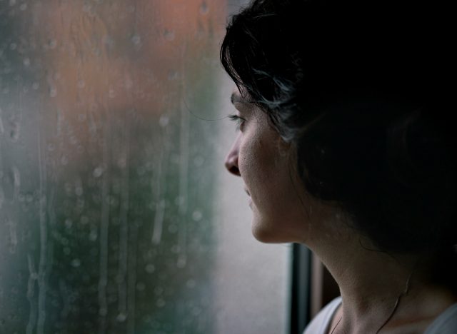woman looking out window at storm