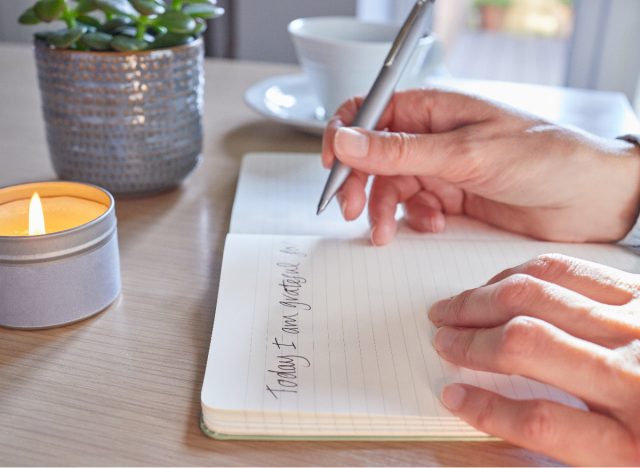 woman writing in gratitude journal, one of the tiny things to massively boost your health