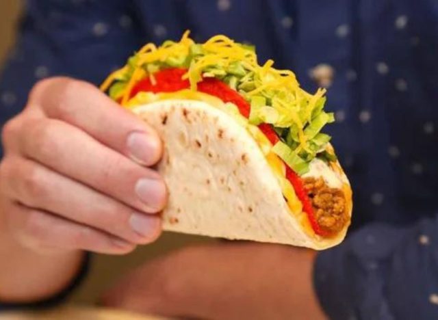 a hand holding a taco bell gordita crunch