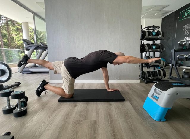 man demonstrating bird-dog exercise to shrink pot belly fat fast