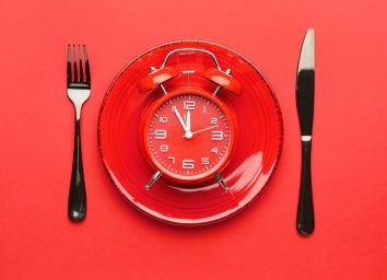 clock on plate with fork and knife, intermittent fasting concept