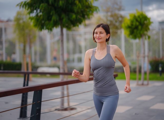 woman power walking outdoors to burn more belly fat