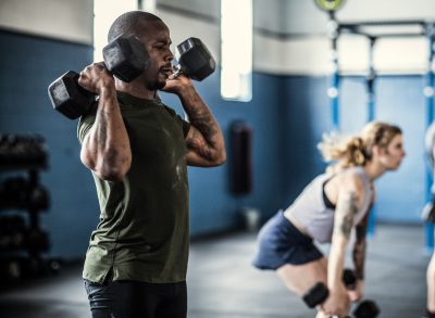 fitness man demonstrating dumbbell workout to slim down a thick waistline