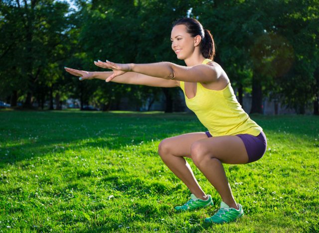 fitness woman performing squats outdoors in sunshine