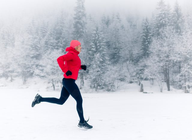 fitness woman running in the snow, demonstrating how to stay fit in the cold