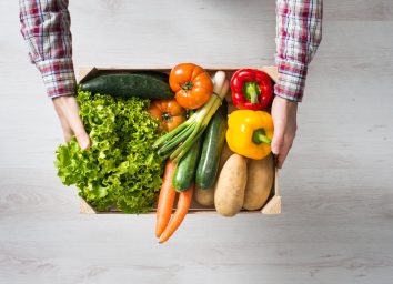 man holding crate of fresh garden vegetables