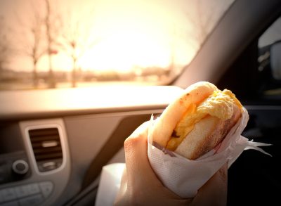 holding breakfast sandwich in car